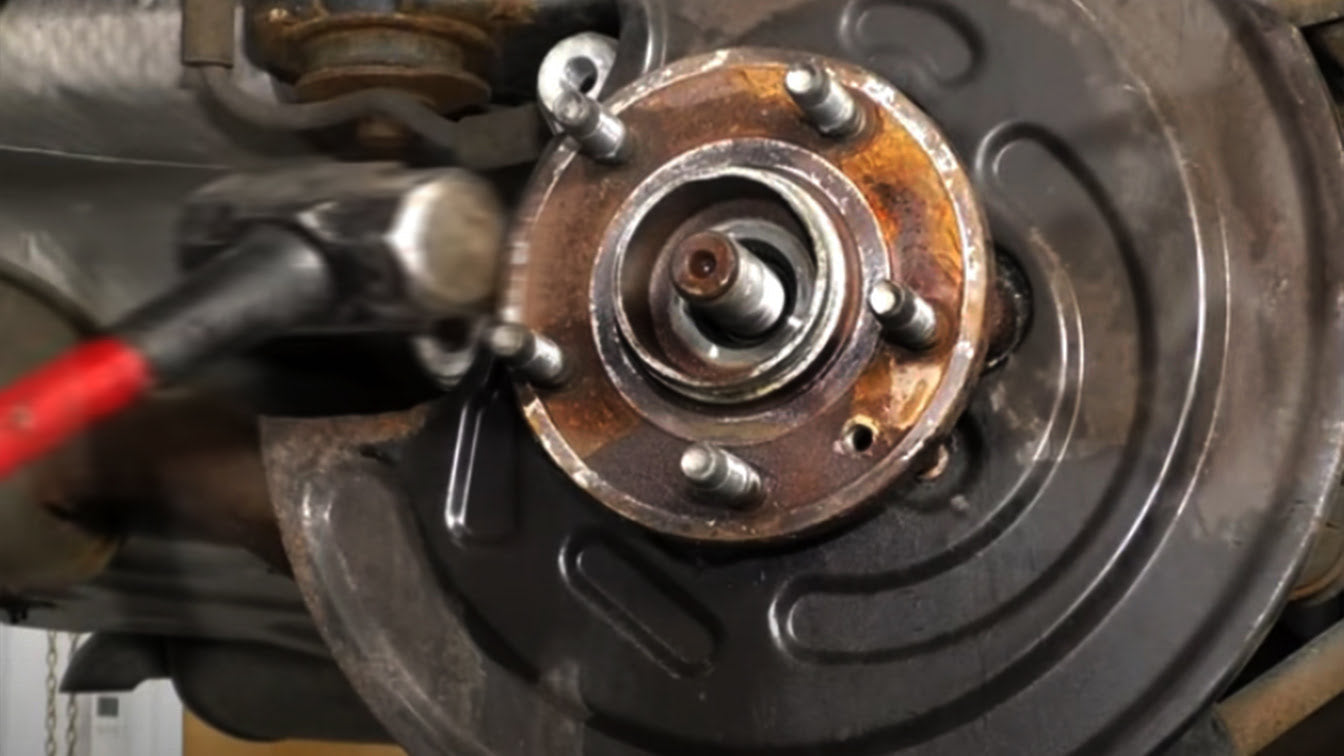 Using a hammer to tap a wheel hub assembly until it can be removed