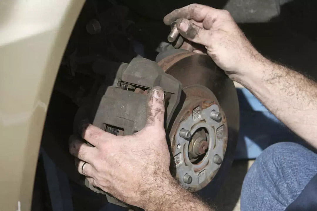 Person removing brake calipers and rotors from car