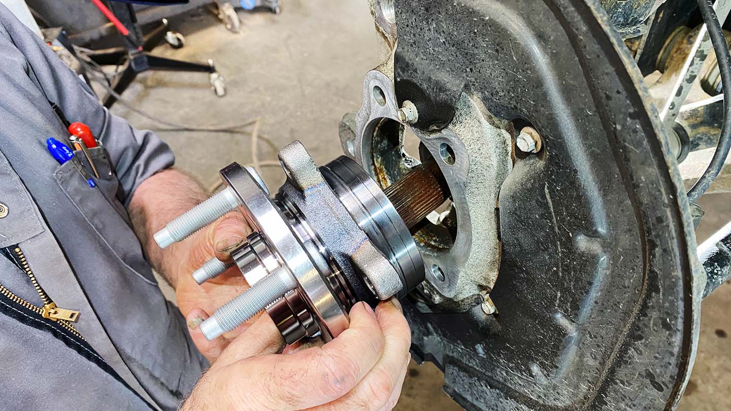 Man holding new wheel hub assembly and lining up axle shaft splines