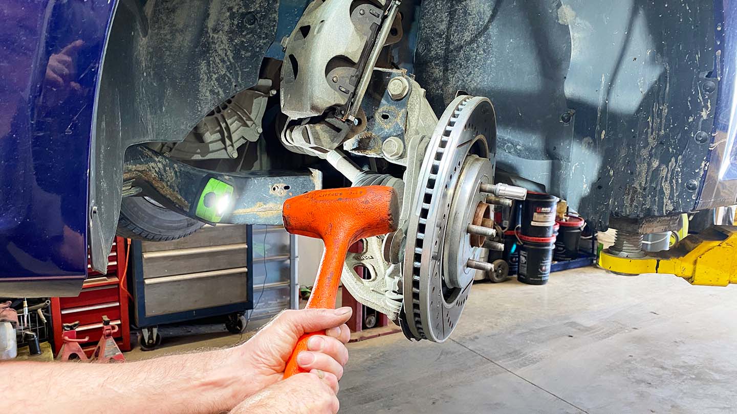 Man swinging hammer against the back of the brake rotor