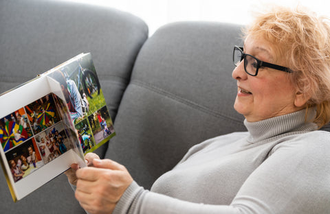 cheerful-senior-female-holding-family-photo-album-sitting-sofa-home-elderly-woman-watching-photobook
