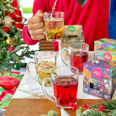 Alibu Tea infusions being served over a table with glasses and a pitcher showing the fruit infusions with Christmas decorations