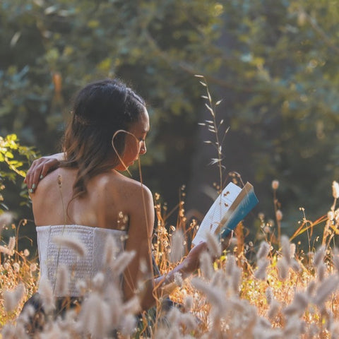 girl sitting in summer field reading book