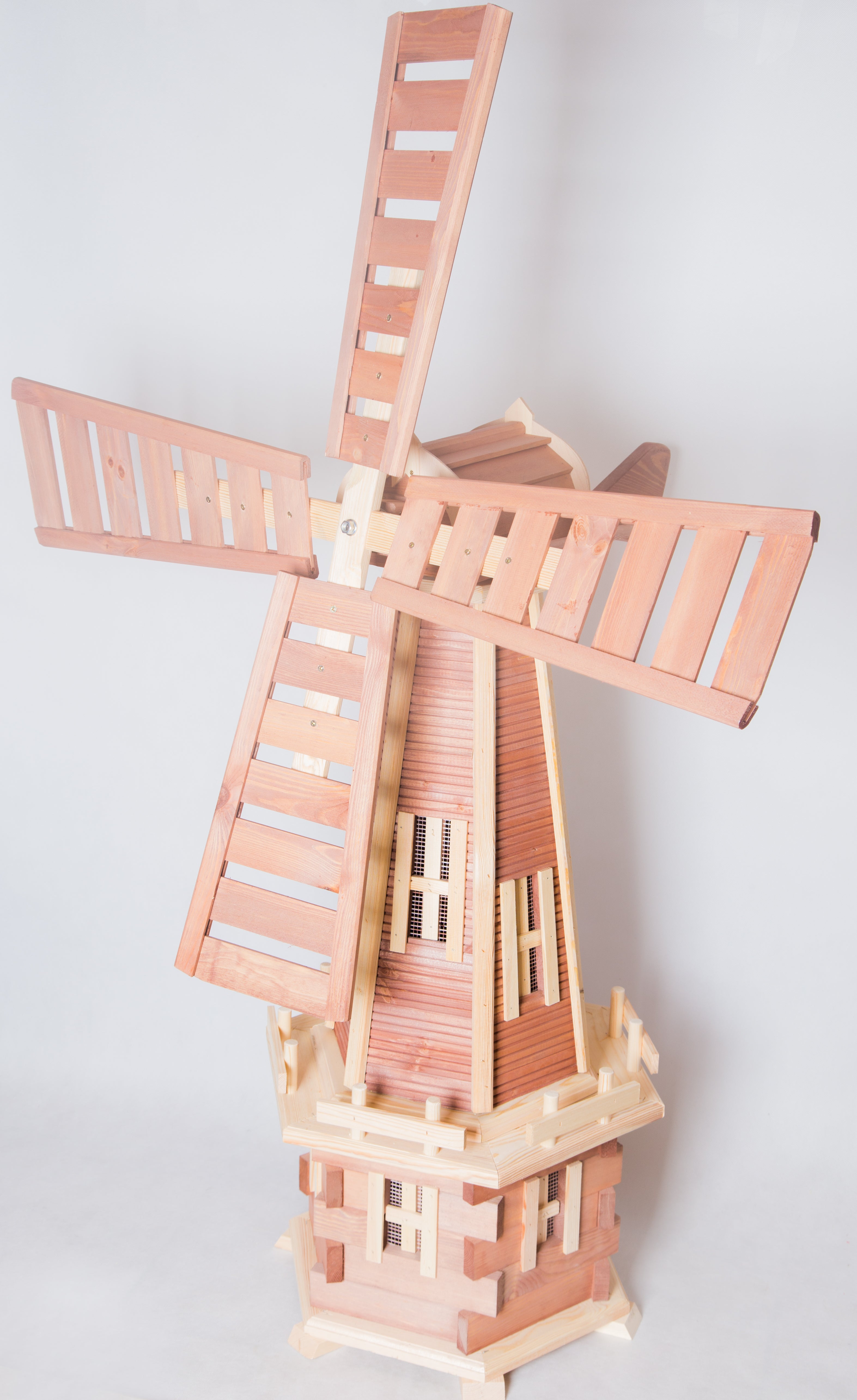 Image: A wooden garden windmill with four blades, standing gracefully in a lush garden. The natural wood texture and intricate craftsmanship add rustic charm to the landscape