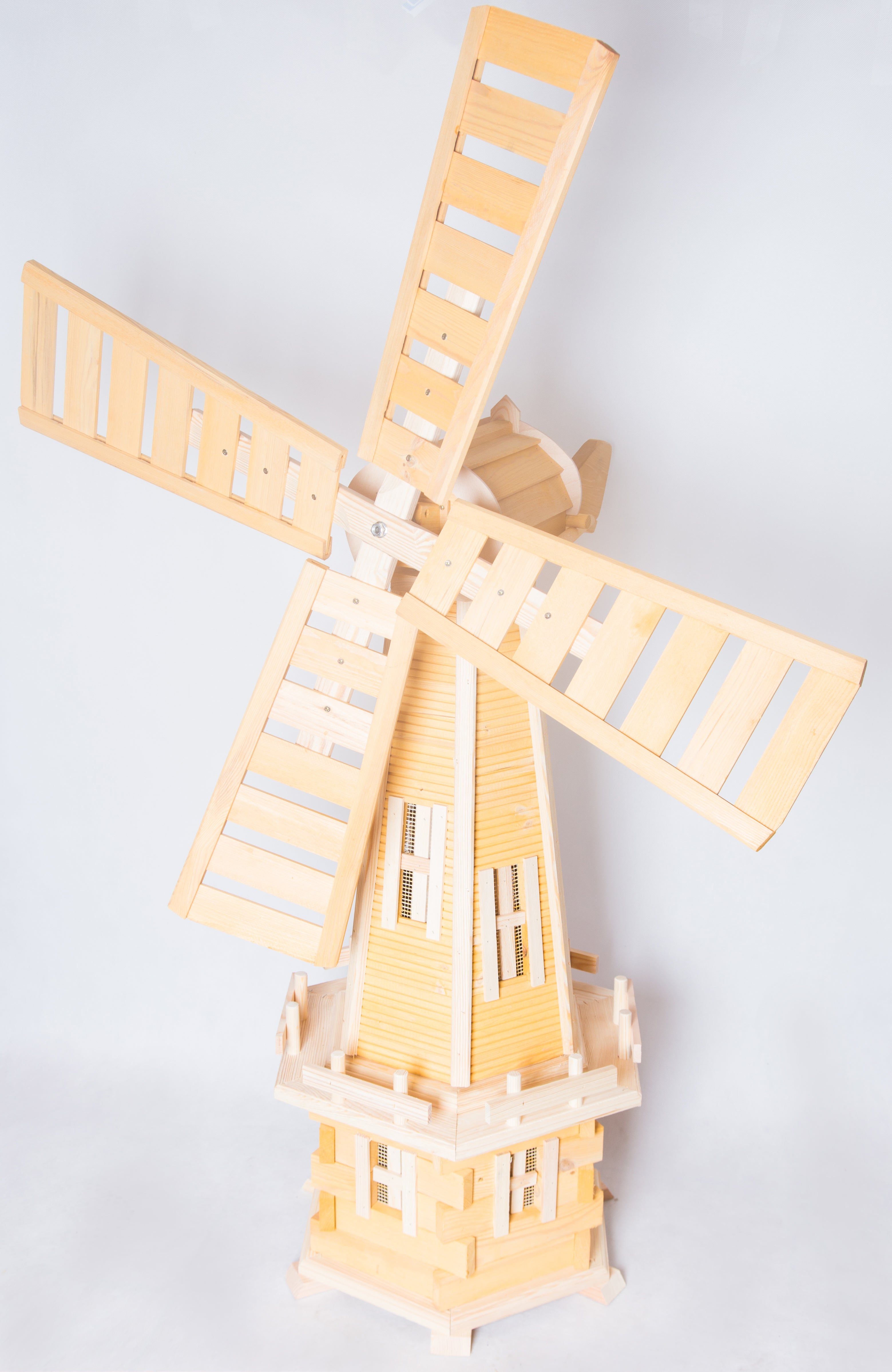 Garden windmill with wooden blades, spinning in the wind to create a picturesque outdoor scene.
