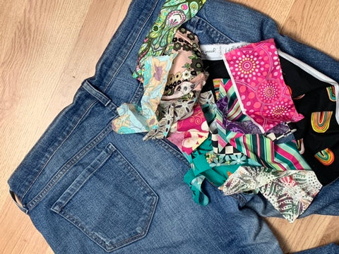 pair of jeans with pile of colorful cotton scraps