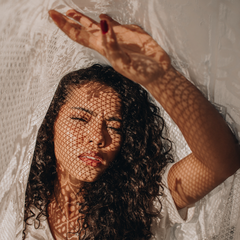 Curly-haired woman finding shade to protect her vibrant curls from the sun