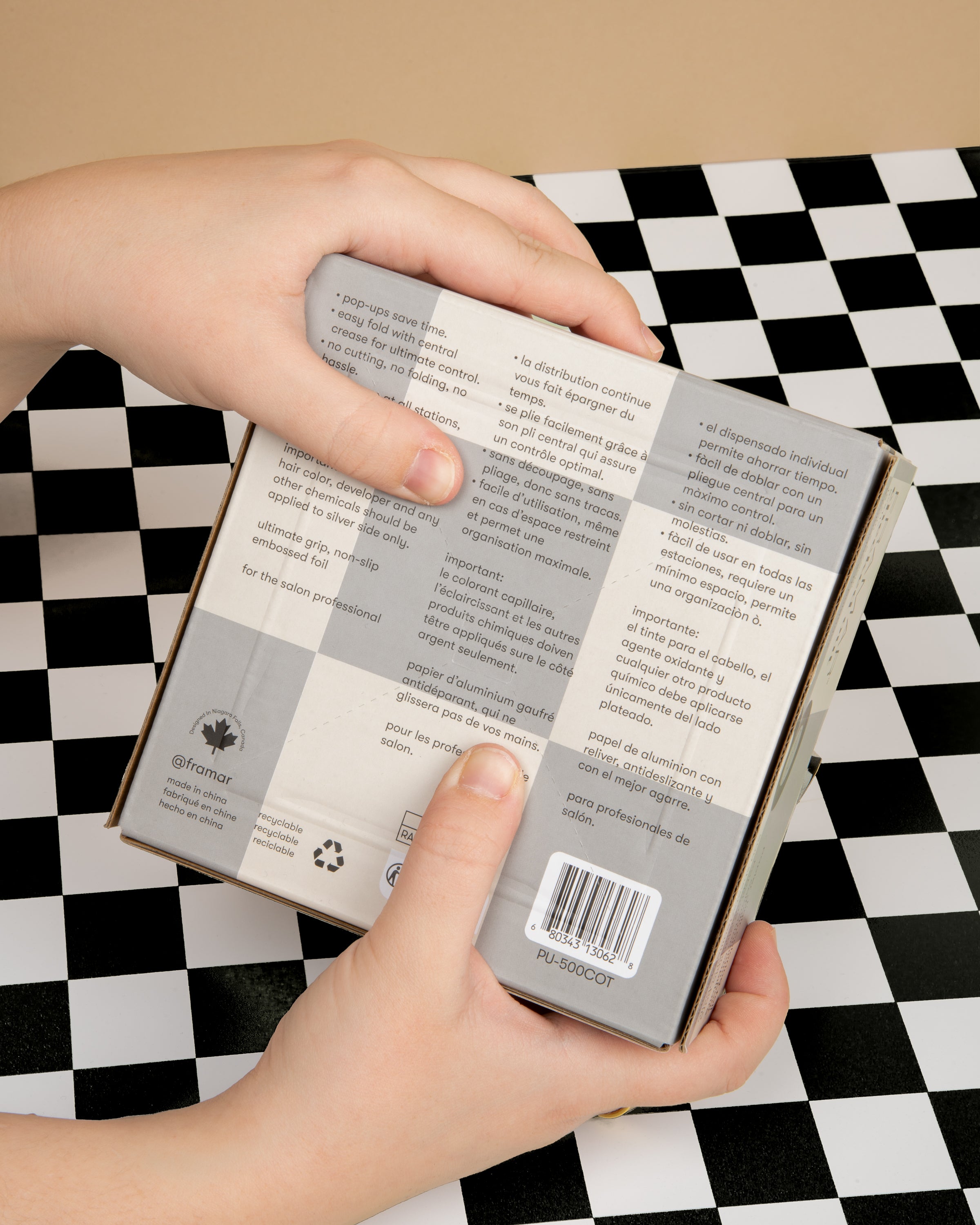 Hands holding a product box with text over a checkered surface.