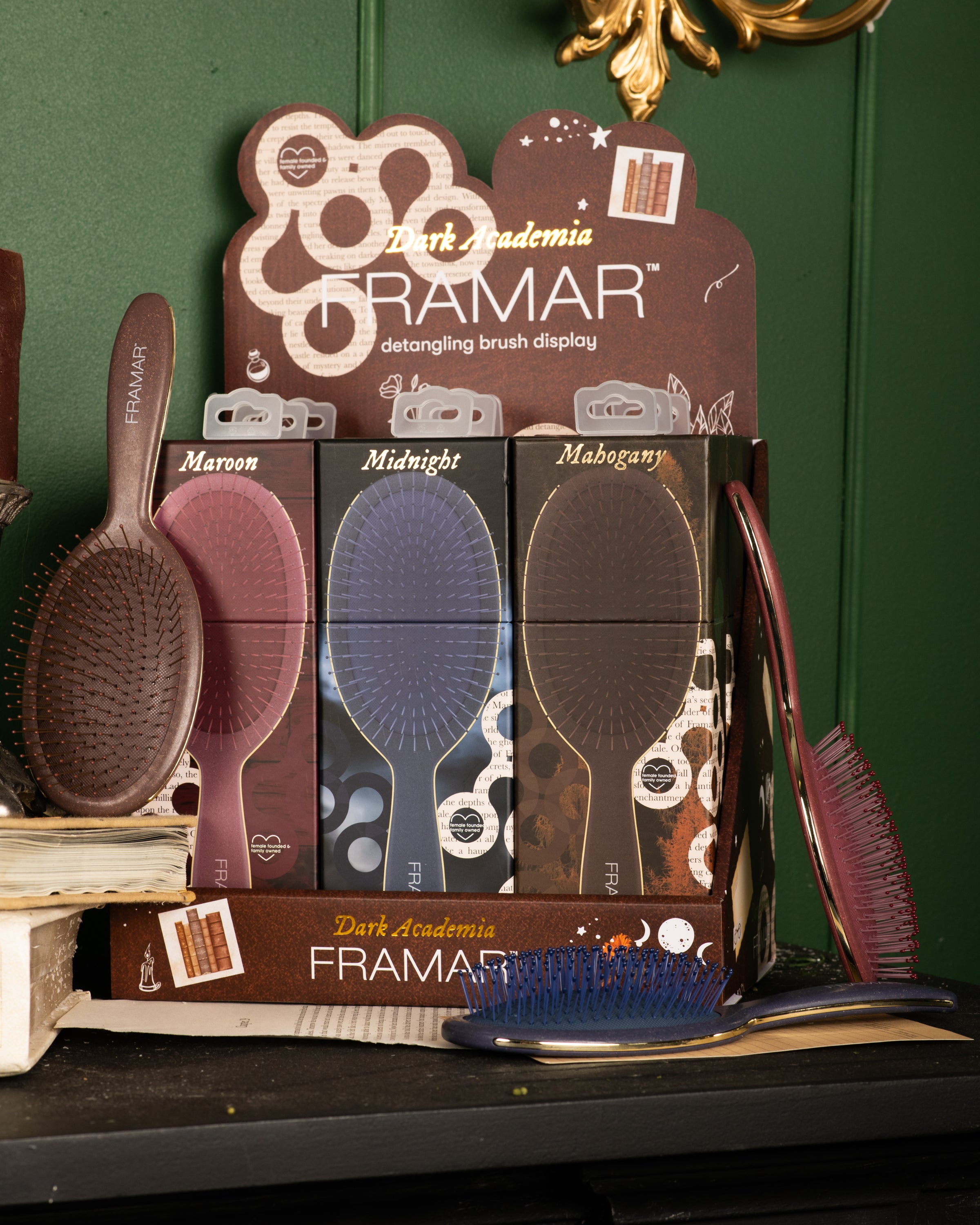 Display of FRAMAR detangling brushes in three colors: Maroon, Midnight, and Mahogany, labeled 'Dark Academia.'