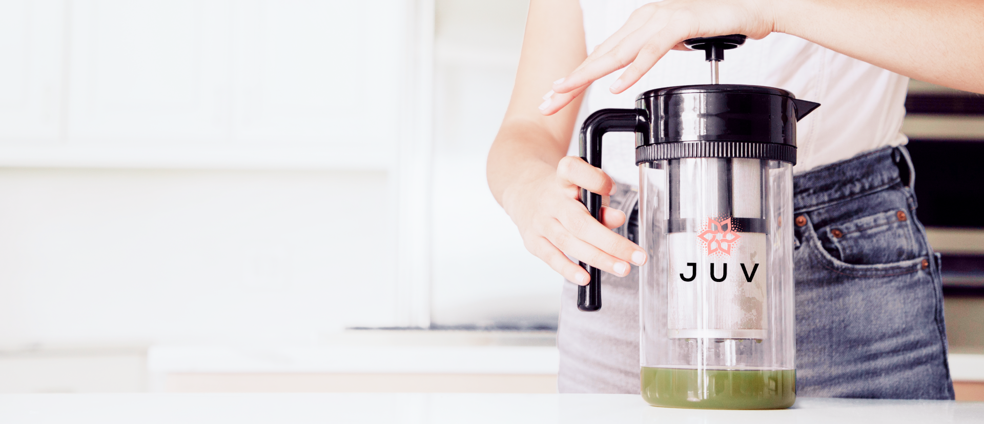 Person using a manual cold brew coffee maker in a kitchen setting.