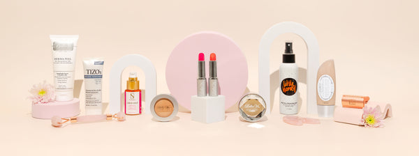 Beauty and skincare products lay side by side with a pink background.