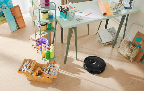 A black Q Revo smart vacuum is cleaning the hard wood floor.