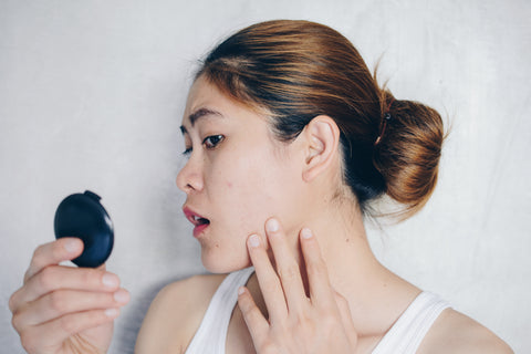 Woman looking in mirror at her skin