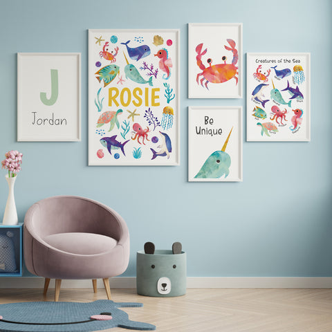 Bright ocean animal themed nursery prints hung in white frames on a gallery wall. 