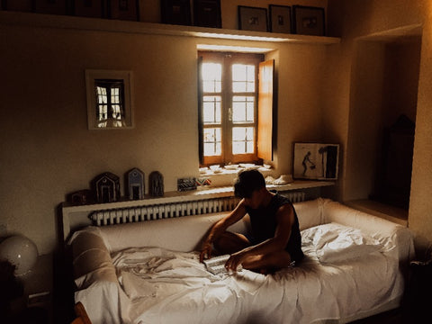 A young man reading a book in his cozy bed in a dimly lit room