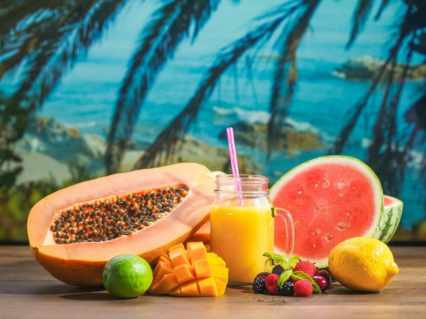 A mango cocktail and a variety of fruits overlooking the ocean
