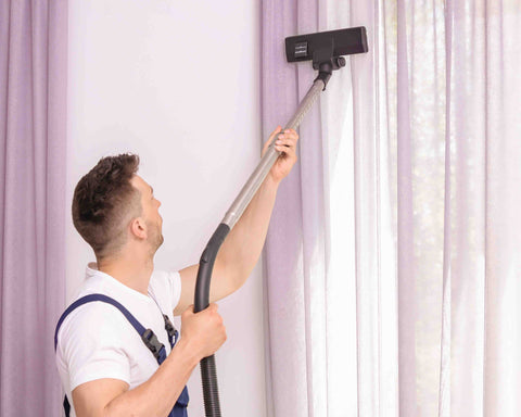 Man cleaning a window curtain