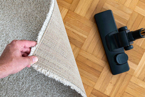 vacuuming an area rug on hardwood floor