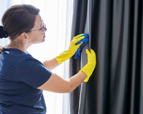 woman cleaning a window curtain