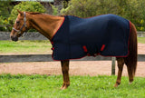 navy blue with red trim cooler modeled on a chestnut horse standing on grass, perfect for winter trail riding