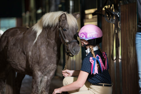 young girl wearing a pink helmet at summer horse camp