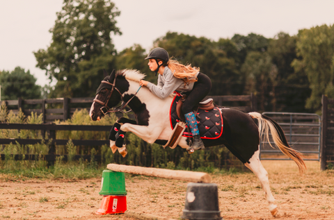 young girl jumping a horse at horseback riding camp