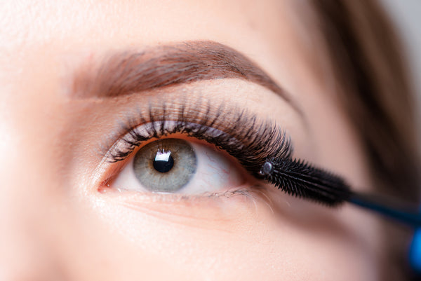 Woman applying mascara to lash extensions