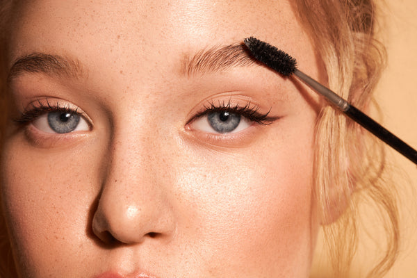 Woman combing eyebrows with a brush closeup