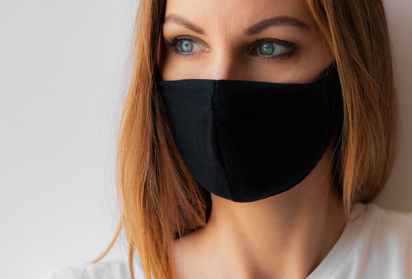 Close-up portrait of a young woman in a black medical mask and white T-shirt