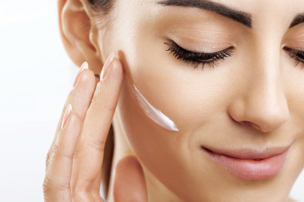 Woman with full eyelashes applying face cream