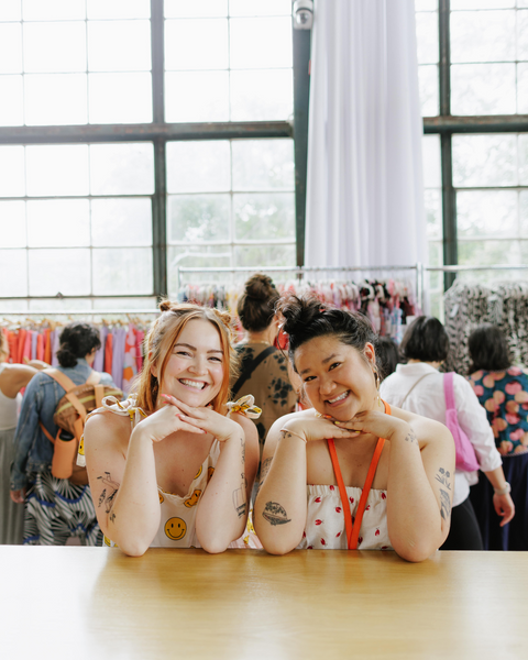 2 people smile at camera with their hands placed under their chin