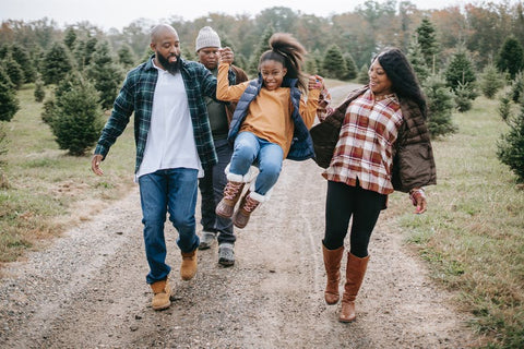 African American mom and dad lifting their child up as they walk along a hiking trail