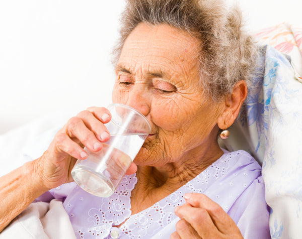 Senior woman taking supplements with glass of water