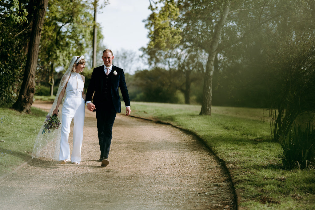 Bride and groom walking through english countryside