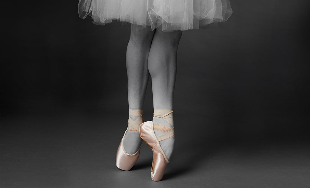 A ballet dancer dancing en pointe in the studio wearing tights, a tutu and Balance Lisse pointe shoes