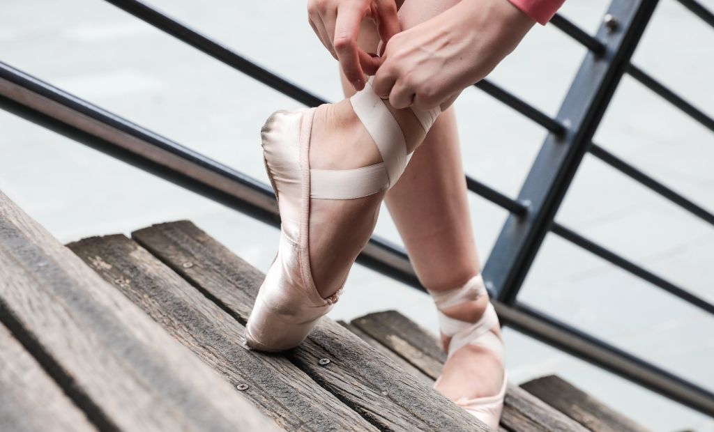 A dancer waiting to go into theatre tieing the ribbons on her BLOCH Pointe Shoes 