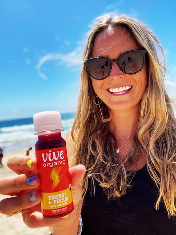 Kelsey holding her favorite shot, Energy and Focus, at the beach