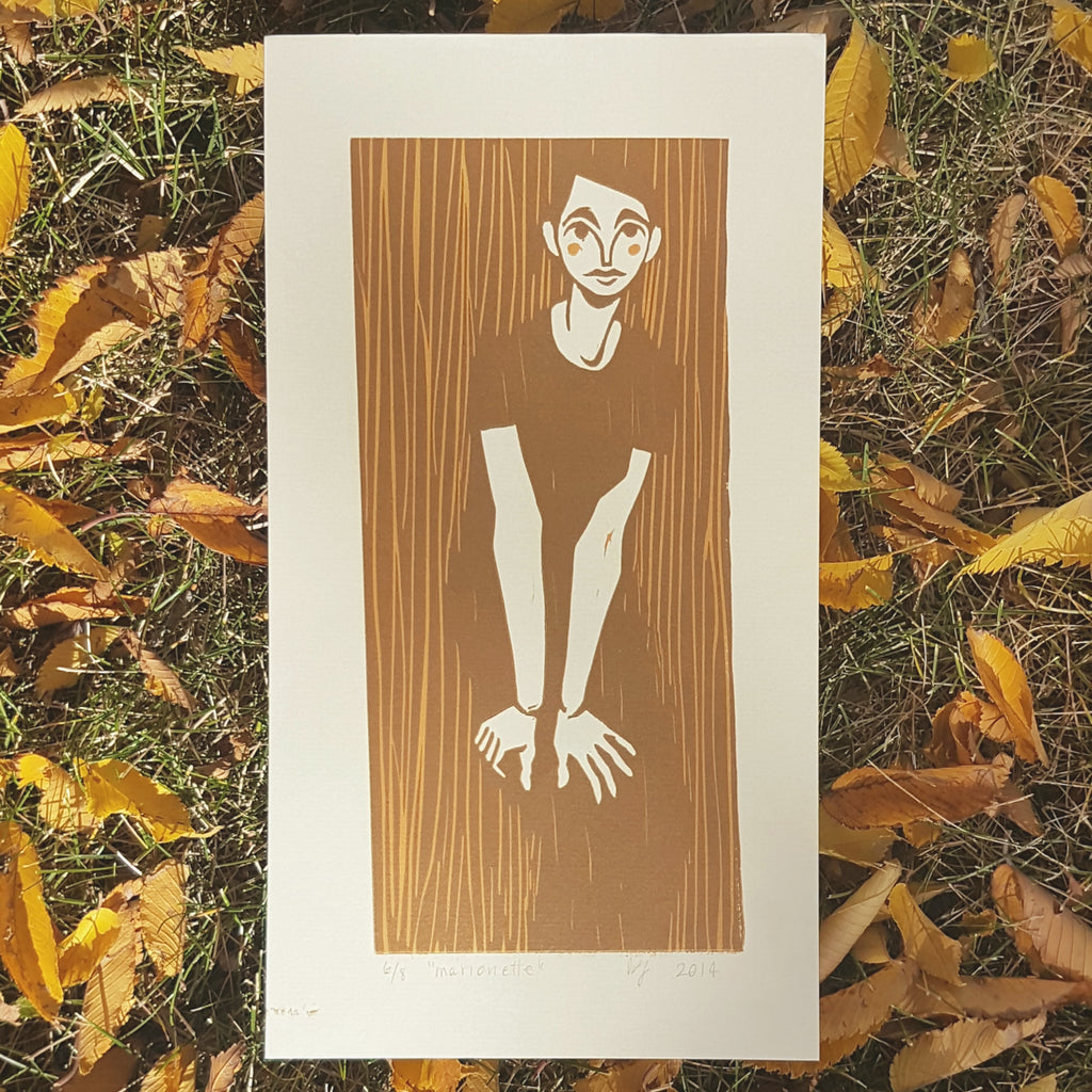 photograph of a print on a pile of yellow fall leaves. the print is a brown and caramel image of an androgynous figure leaning over with their hands on thir knees. it has a folk-type aesthetic with basic shapes and quick lines