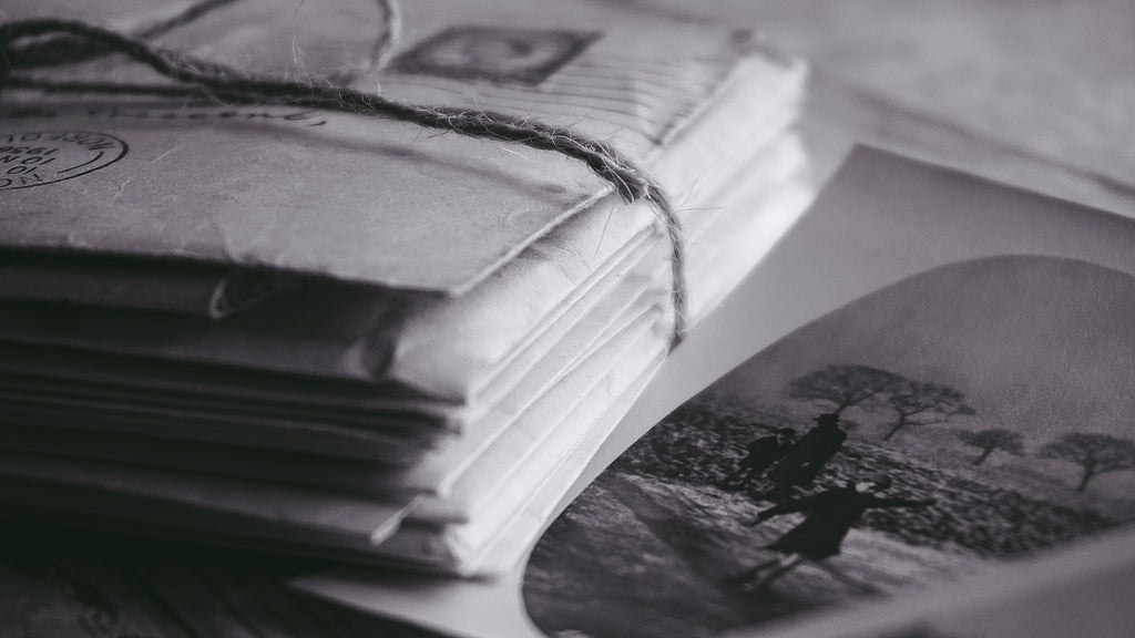 stack of letters tied with twine, an old, oval framed black and white photo of a skaterbeside