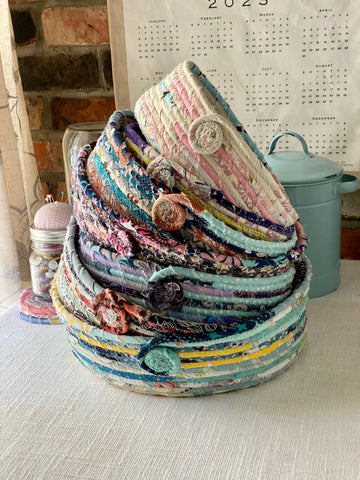 stack of handmade fabric storage baskets with a pin cushion and jar of buttons