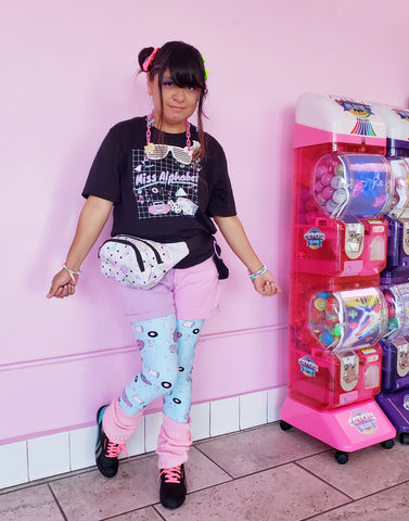 woman with modeling leggings with pink boombox print, pink wall in back, next to a bubblegum machine