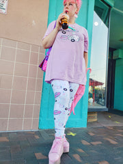 woman modeling brightly colored boombox leggings and t-shirt, sipping tea