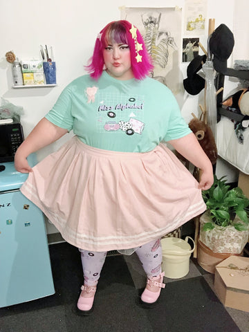 Non binary pink haired person modeling t-shirt and leggings
