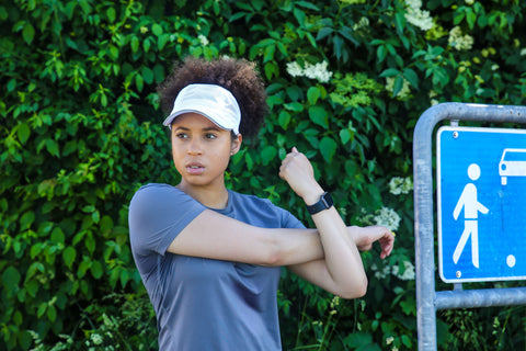 Natural Hair Girl preparing for run in Dri Fit backless white running hat