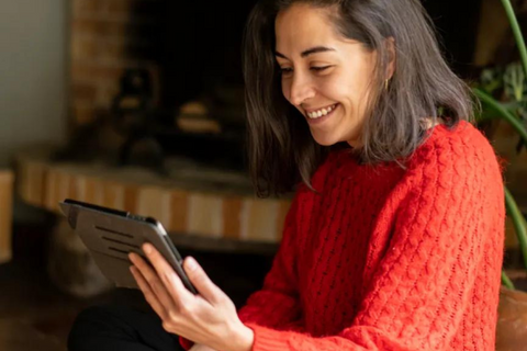 a woman wearing a red sweater looks at something on an ipad screen