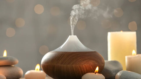 wooden oil diffuser with candles next to it source: sixtyandme.com