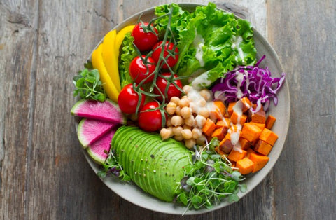 bowl of heathy foods like cabbage, avocado, sweet potato, chickpeas, bell pepper, and lettuce