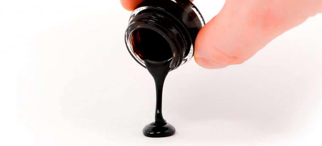 Shilajit resin being poured from a bottle container onto a a surface
