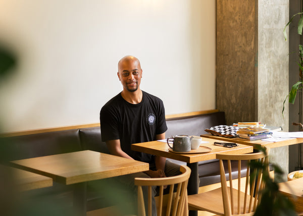 Man smiling and sitting at a table in a cafe.