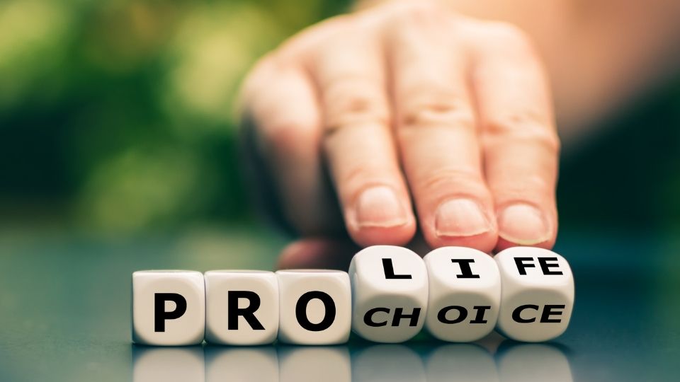 Hand turns dice and changes the expression "pro choice" to "pro life".